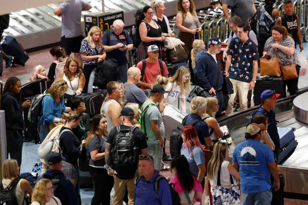 People wait for their luggage at a baggage carousel at Harry Reid International Airport, Friday ...