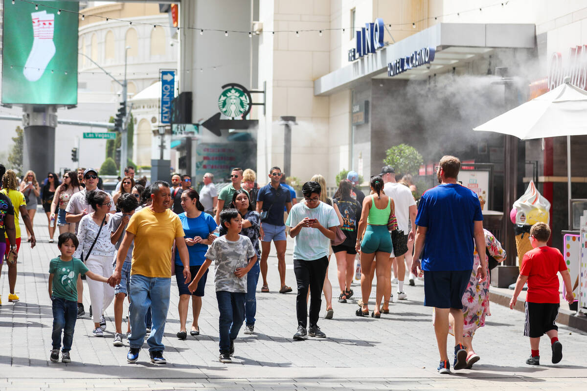 Crowds brave the heat along the Strip by walking through a row of misters on Monday, July 31, 2 ...