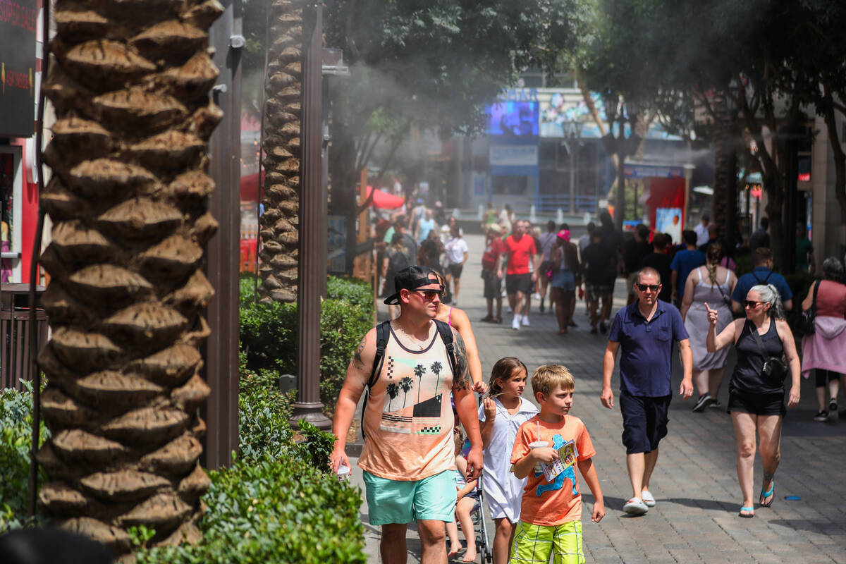 People brave the heat along the Strip by walking through a row of misters on Monday, July 31, 2 ...
