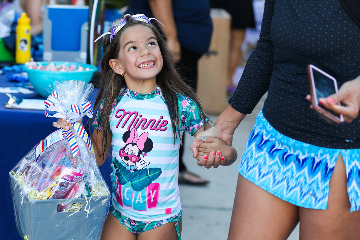 Lyanna S., 6, cheerfully looks up to her mother after winning a raffle for school supplies at t ...
