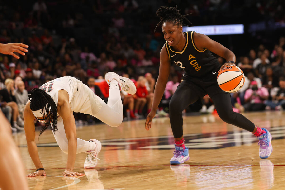 Atlanta Dream guard Allisha Gray (15) stumbles on the court in front of Las Vegas Aces guard Ch ...