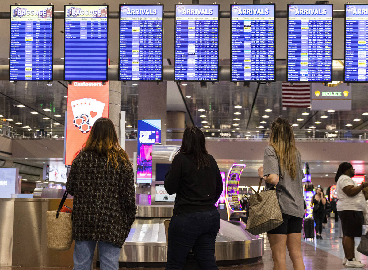 Passengers look at flight departure and arrival information on electronic monitors in Terminal ...