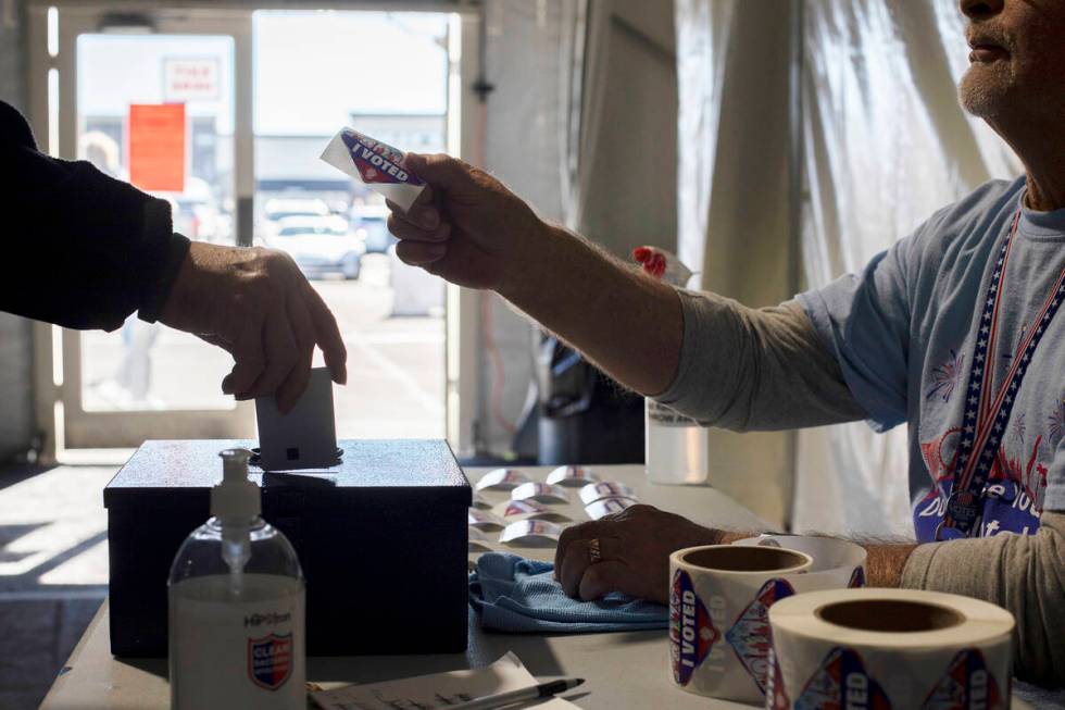 Volunteer Dennis Kepper hands out stickers on the last day of early voting in November 2022 at ...