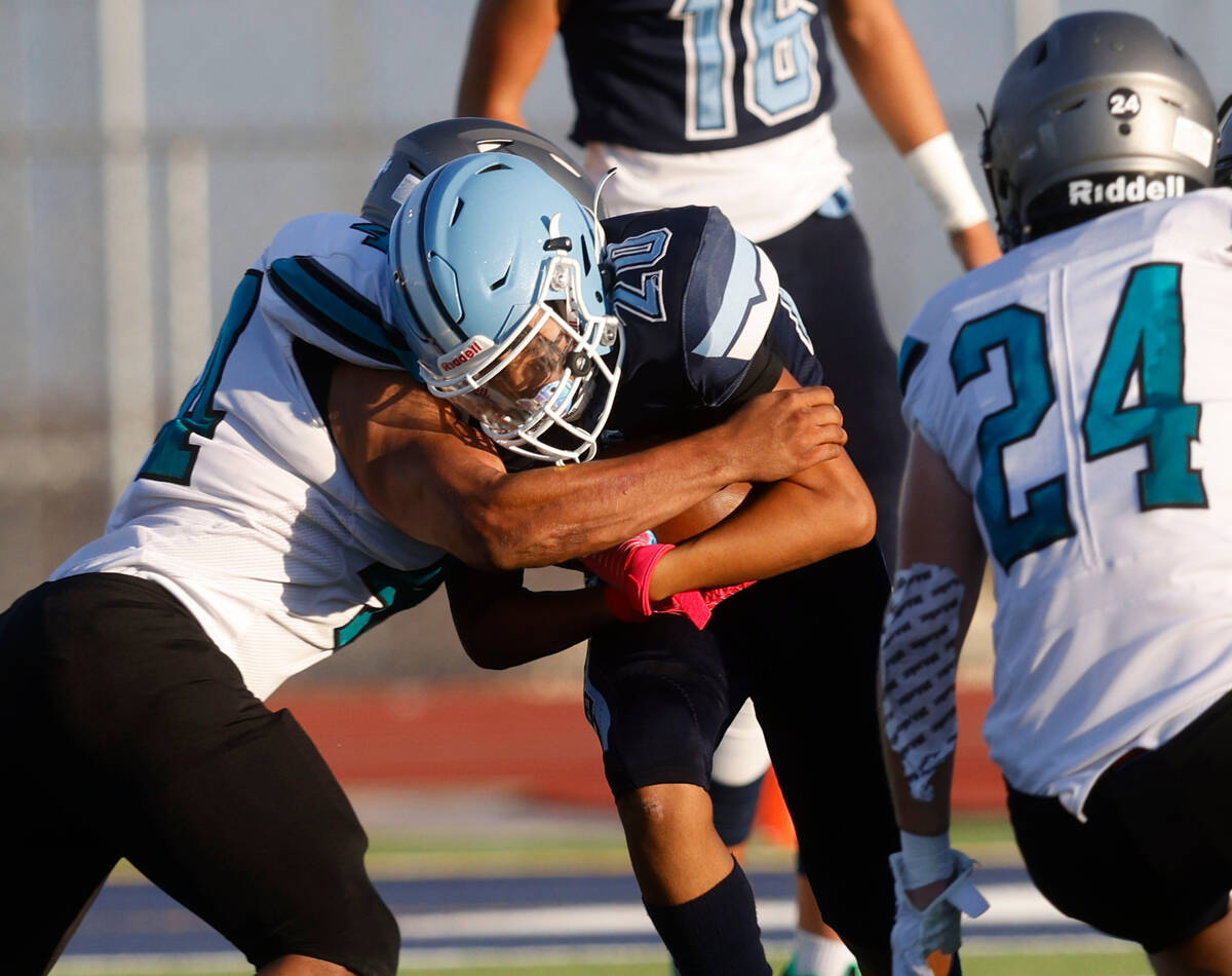 Centennial High School's Evan Montero center, is tackled by Silverado High School's Chris Feder ...