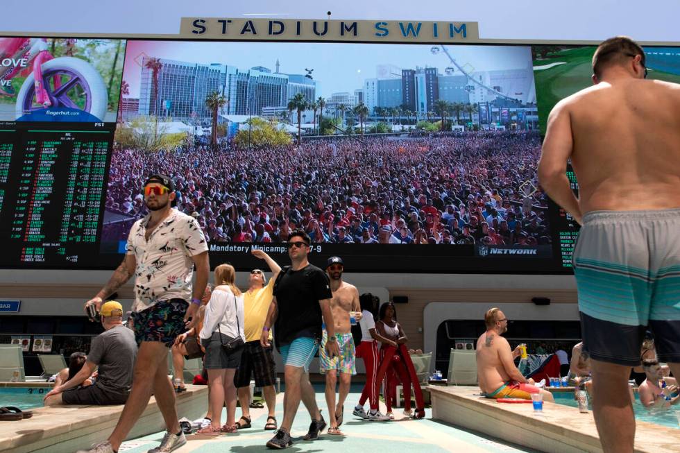 The crowd at the NFL draft on the Las Vegas Strip is seen on the screen at Stadium Swim as pool ...