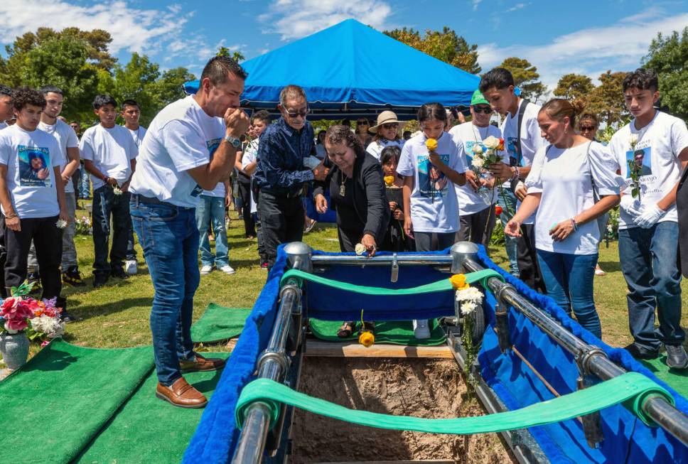 Rudolfo Naranjo, left, weeps as family members toss flowers onto the lowered casket of his on A ...