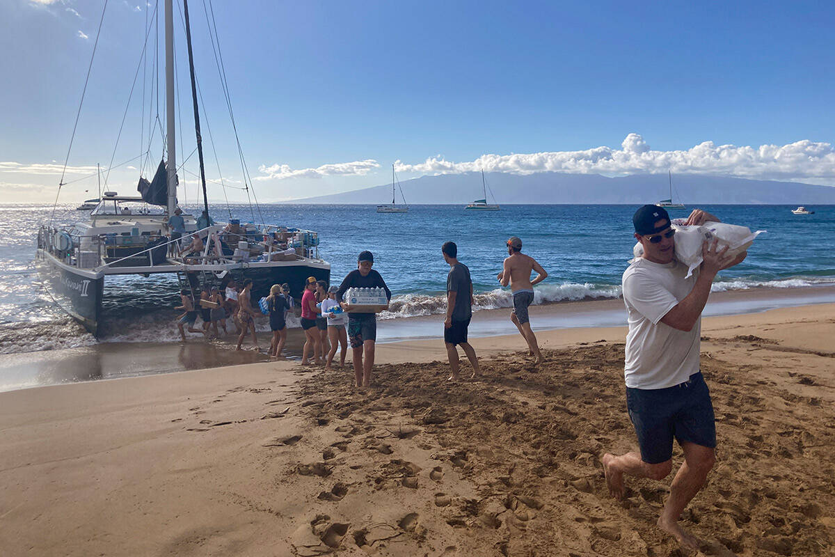 A group of volunteers who sailed from Maalaea Bay, Maui, form an assembly line on Kaanapali Bea ...