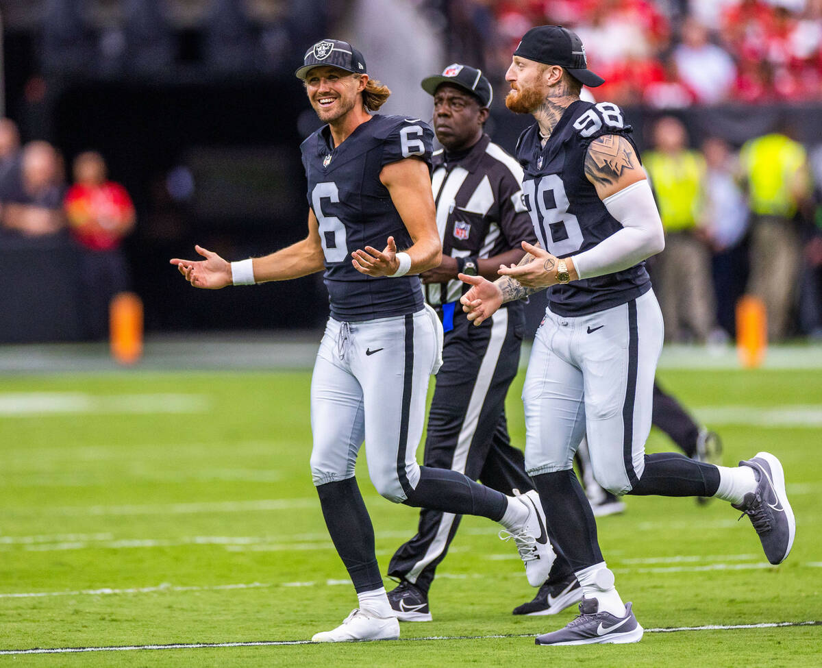 Raiders punter AJ Cole (6) and defensive end Maxx Crosby (98) run off the field after the coin ...