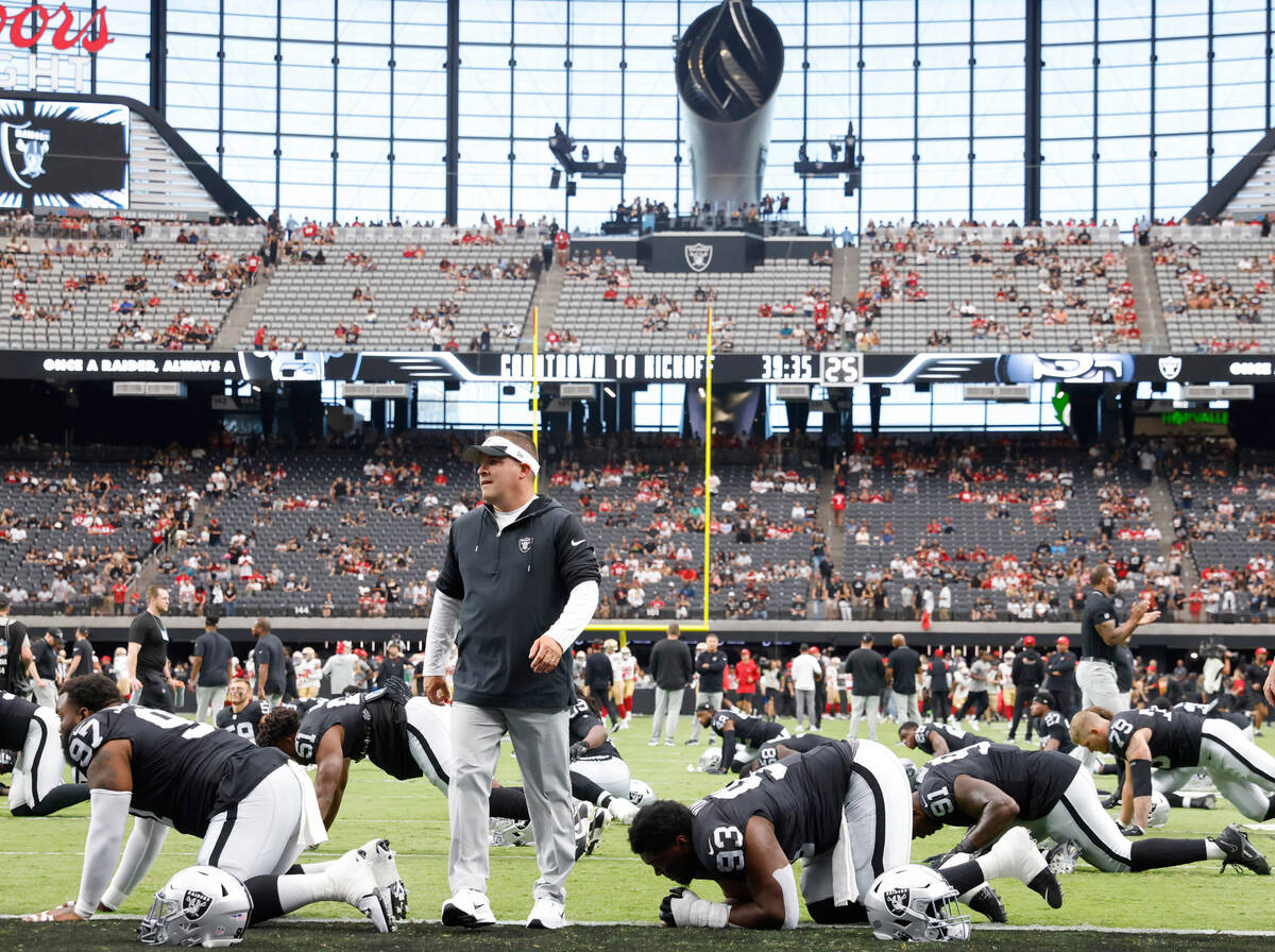 Raiders head coach Josh McDaniels watches as his players stretch prior to an NFL preseason foot ...