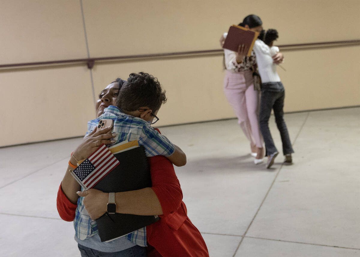 Patricia, of El Salvador, hugs her son after her naturalization ceremony during halftime of a L ...