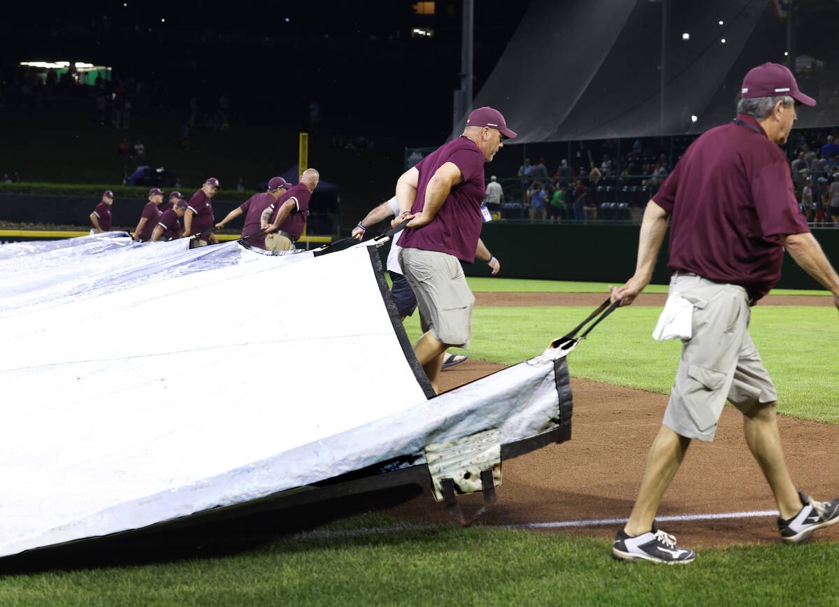 Members of the grounds crew cover the field with a tarp during a rain delay during the Little L ...