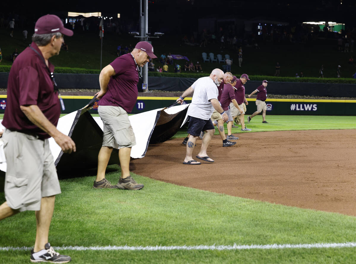 Members of the grounds crew cover the field with a tarp during a rain delay during the Little L ...