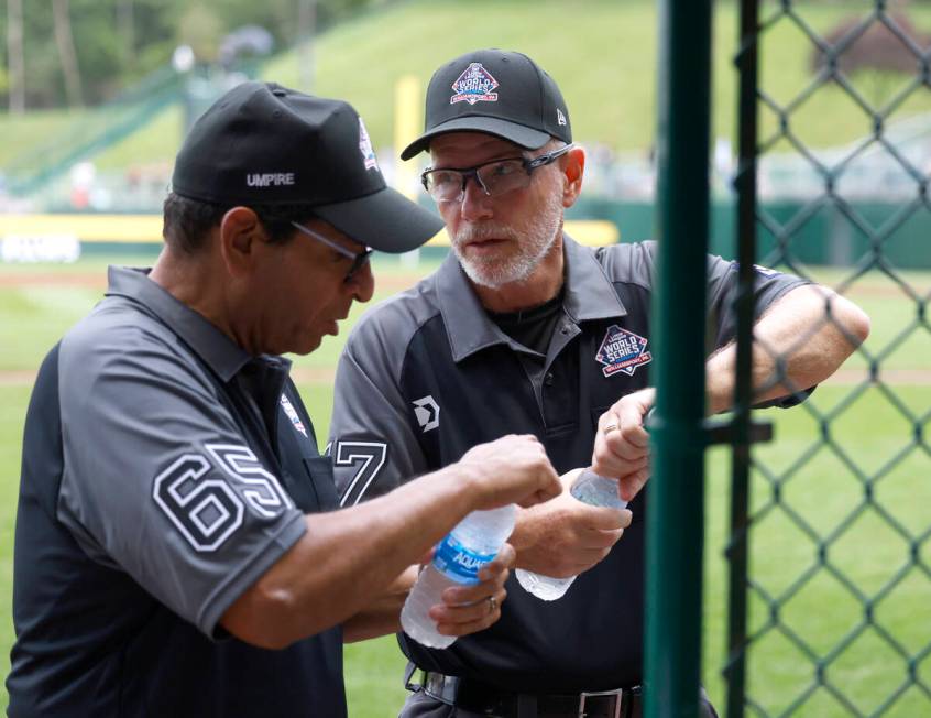 Ben Sprague of Las Vegas, right, and Andy Pagan, volunteer umpires, take water break during the ...