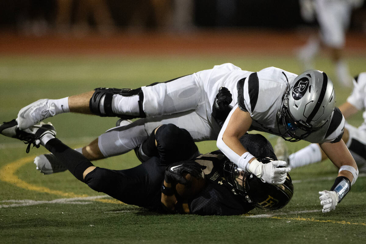 Faith Lutheran wide receiver Jaxon Cope, bottom, is tackled by a Palo Verde player that could n ...