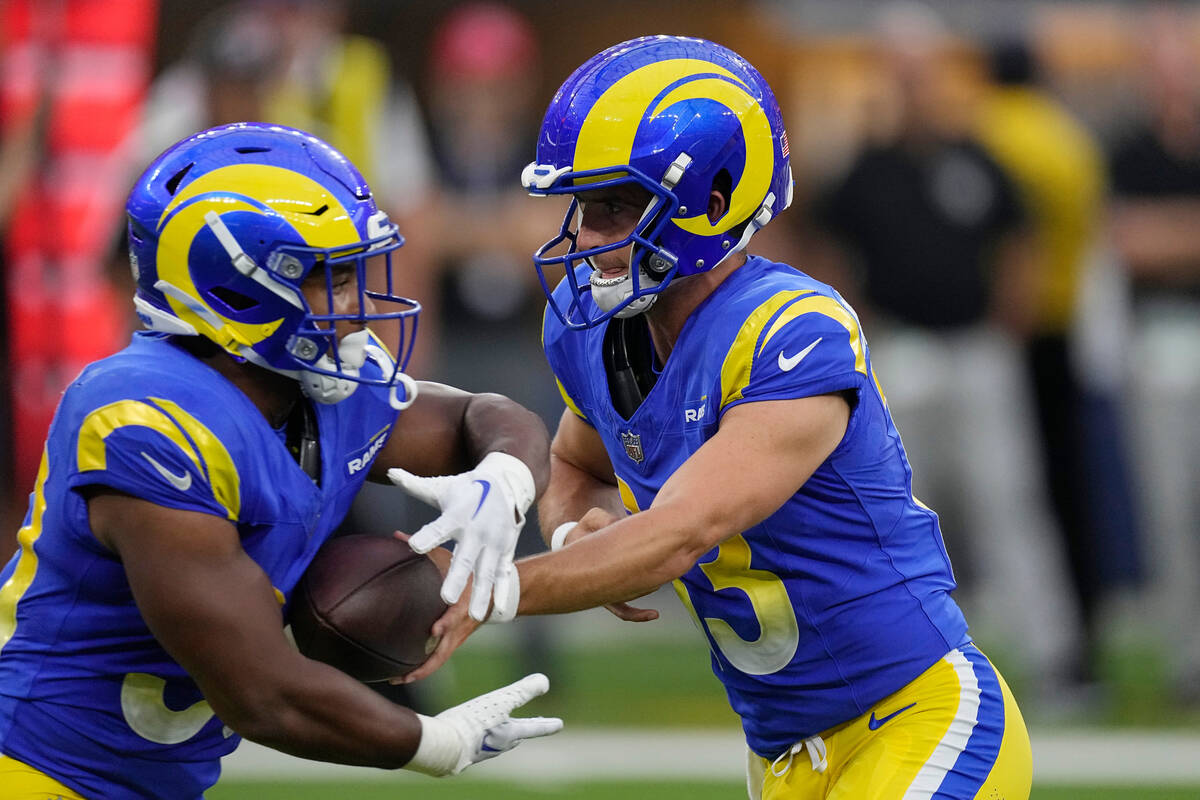 Los Angeles Rams quarterback Stetson Bennett, right, hands off to running back Ronnie Rivers du ...