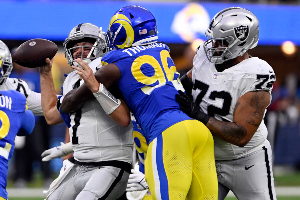 Las Vegas Raiders quarterback Brian Hoyer, left, is sacked by Los Angeles Rams linebacker Keir ...