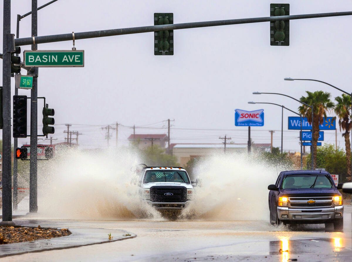 A truck throws up lots of standing water in the intersection along South Highway 160 at Basin A ...