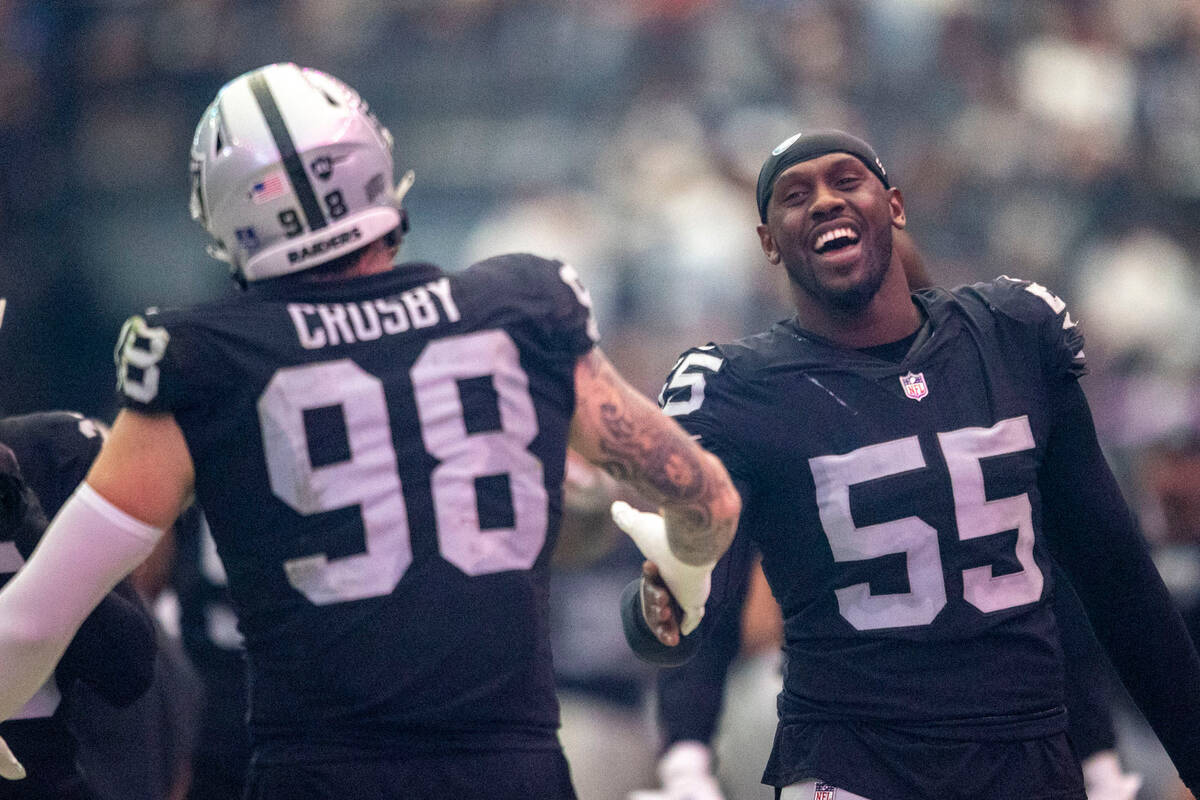 Raiders defensive end Chandler Jones (55) greets Raiders defensive end Maxx Crosby (98) on the ...