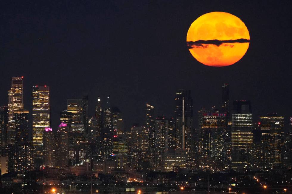 FILE - A supermoon rises through clouds over the skyline of lower Manhattan, Aug. 1, 2023, as s ...