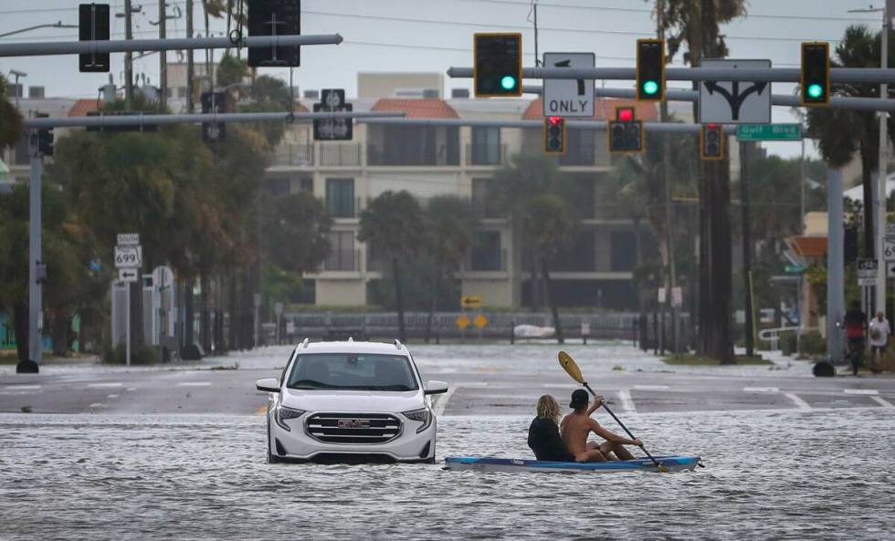 People kayak past an abandon vehicle in the intersection of Boca Ciega Drive and Pasadena Avenu ...