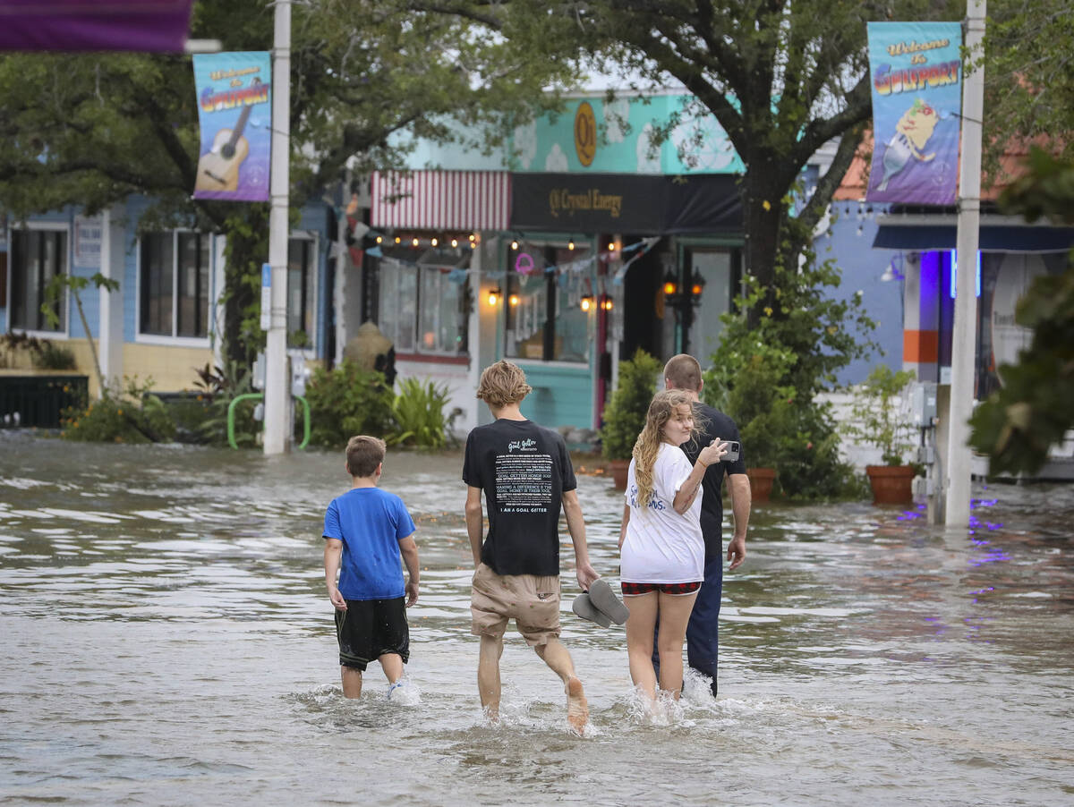 A group wades into a flooded Beach Boulevard near 31st Avenue, Wednesday, Aug. 30, 2023, in Gul ...