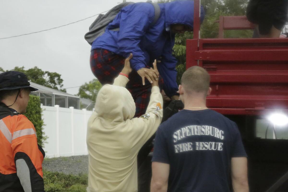 Janecia Wallace, 18, climbs down a ladder with the help of her brother, Julian Wallace, 13, aft ...