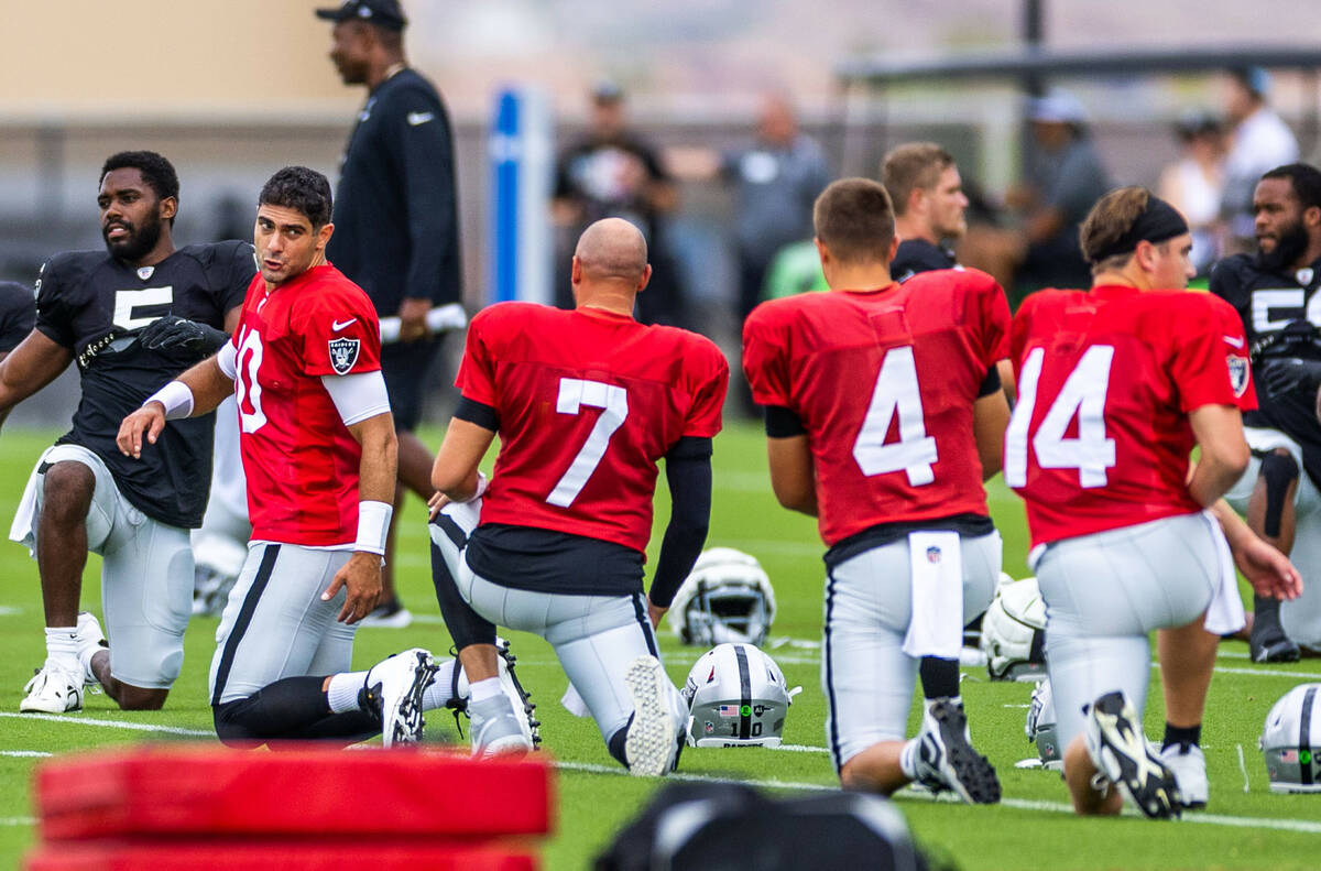 (From left) Raiders quarterback Jimmy Garoppolo (10) and Brian Hoyer (7) talk while stretching ...