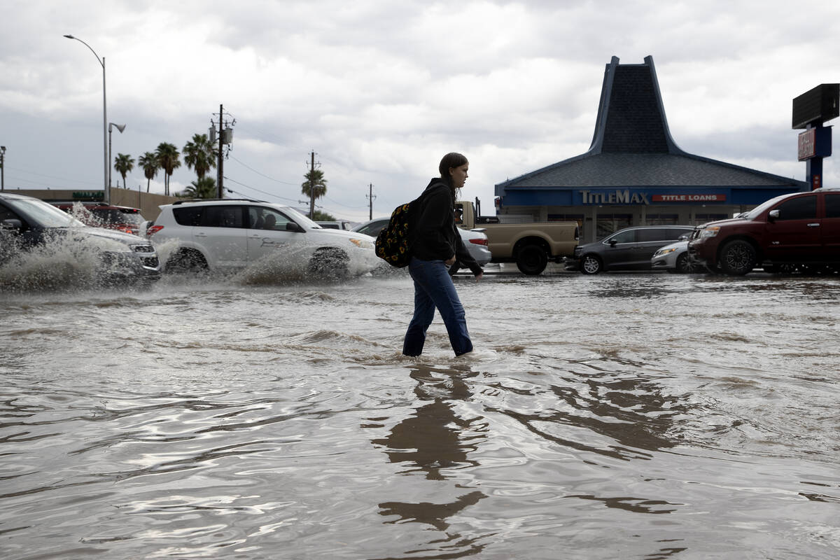 A pedestrian walks down a flooded sidewalk on South Eastern Avenue on Friday, Sept. 1, 2023, in ...