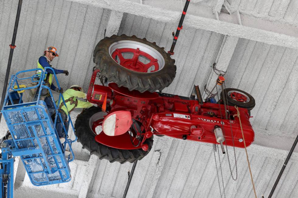 Chaz Woods, left, and Kaden Lizares install an antique tractor on the ceiling of the under cons ...