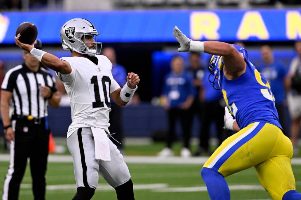 Las Vegas Raiders quarterback Jimmy Garoppolo, left, throws downfield under pressure from Los A ...