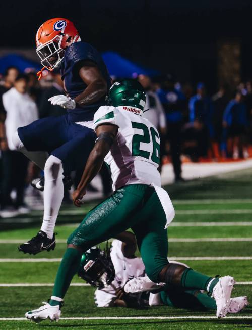 Bishop Gorman tight end Elija Lofton (9) keeps the ball in his possession as he jumps over a Mi ...