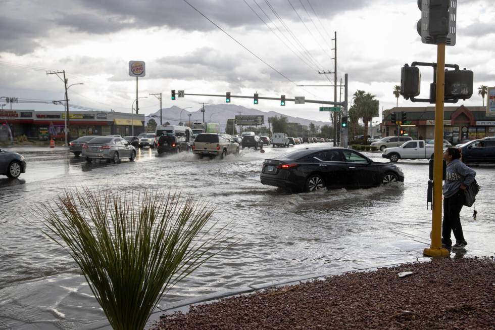 East Sahara Avenue and South Eastern Avenue is flooded while a pedestrian waits to cross the st ...