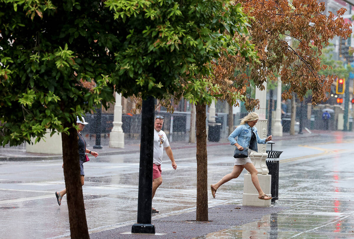 People brave the rain on East Fremont Street in downtown Las Vegas on Friday, Sept. 1, 2023. (K ...