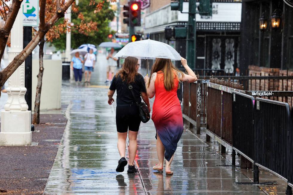 People brave the rain on East Fremont Street in downtown Las Vegas on Friday, Sept. 1, 2023. (K ...