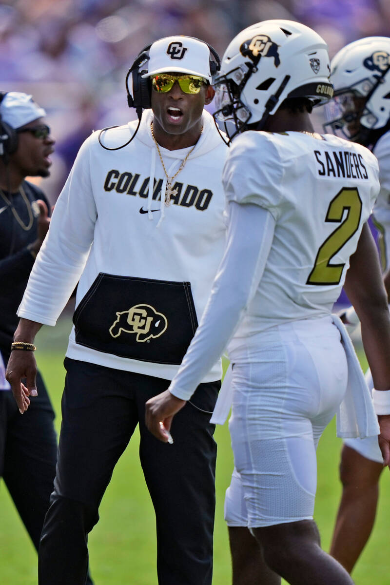 Colorado head coach Deion Sanders, right, talks to his son quarterback Shedeur Sanders (2) duri ...