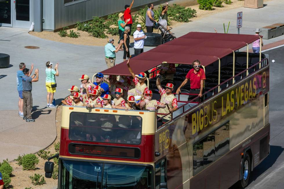 The Henderson Little League team and coaches wave to fans along the parade route on the way to ...