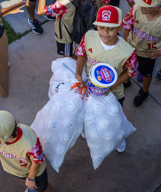 Henderson Little League team player JoJo Dixon (14) readies to enter their bus with a tub of bu ...