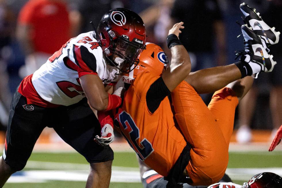 Bishop Gorman quarterback Micah Alejado (12) flies through Centennial’s defense to attem ...