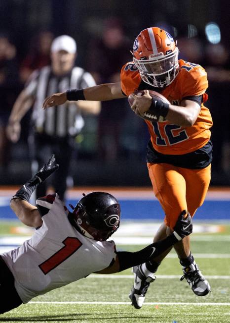 Bishop Gorman quarterback Micah Alejado (12) runs through the grasp of Centennial cornerback Ta ...