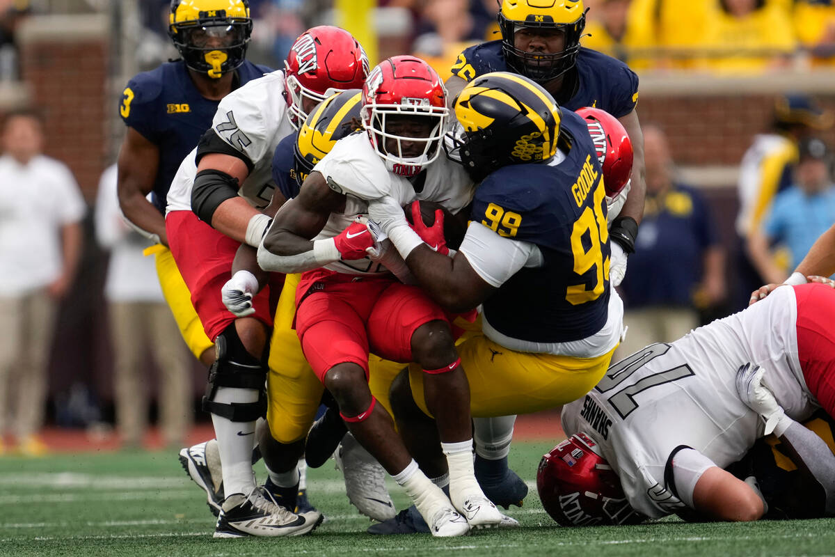 UNLV running back Jai'Den Thomas (22) is stopped by Michigan defensive lineman Cam Goode (99) i ...