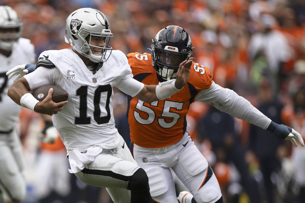 Raiders quarterback Jimmy Garoppolo (10) runs with Denver Broncos linebacker Frank Clark (55) i ...