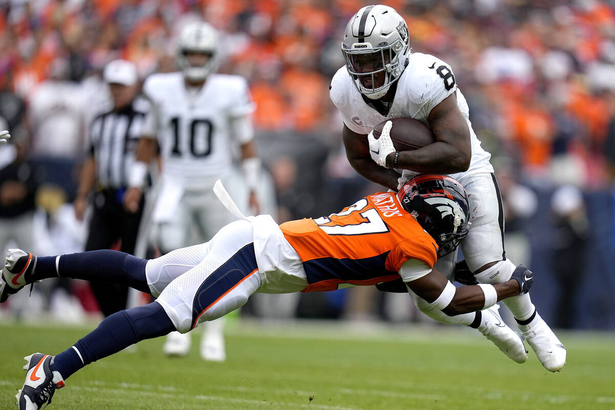 Las Vegas Raiders running back Josh Jacobs (8) is hit by Denver Broncos cornerback Damarri Math ...