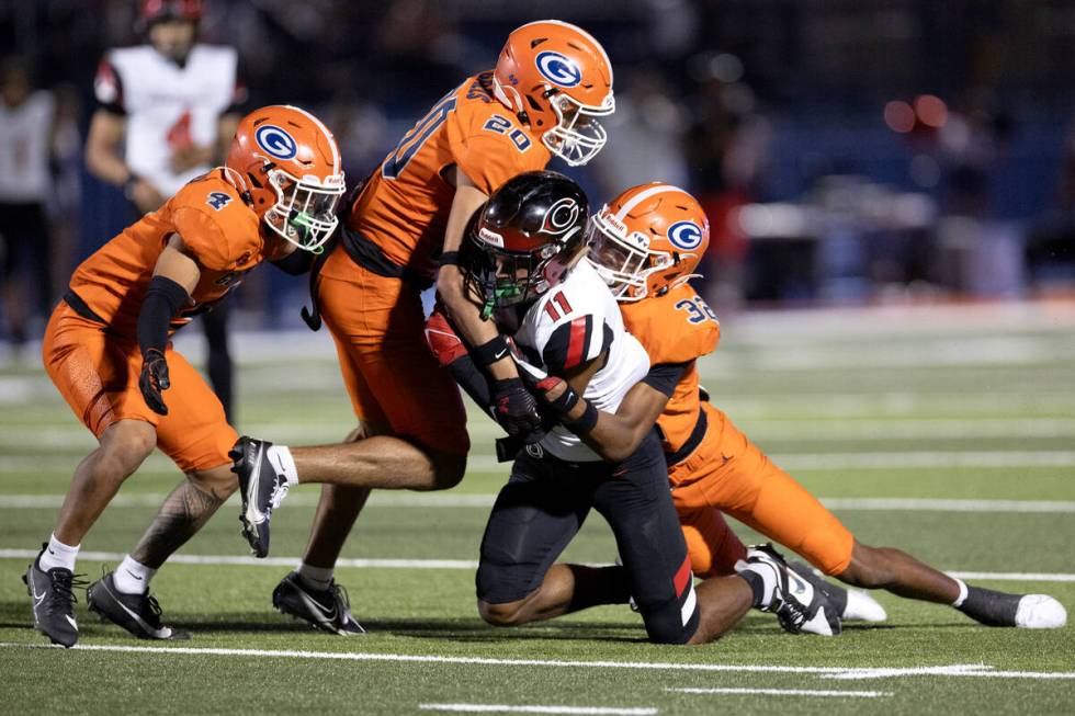 Bishop Gorman defenders Zyzaiah Duncan (4), Alexander Perez (20) and Hayden Stepp (32) take dow ...