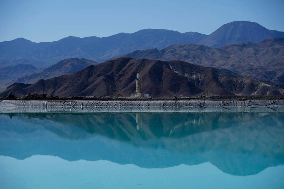 Mountains and a liming facility are reflected in a brine evaporation pond at Albemarle Corp.'s ...