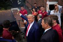 Former President Donald Trump holds a spatula with a hamburger on it as he works the grill duri ...