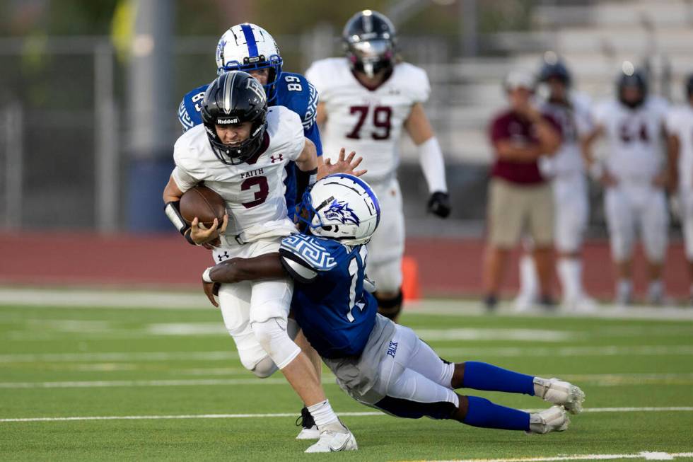 Faith Lutheran quarterback Garyt Odom (3) is tackled on by Basic’s Jaiden Forby (13) dur ...