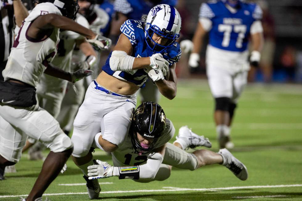 Basic running back Boston Wren (24) is tackled by Faith Lutheran fast safety Gavin Day (12) dur ...