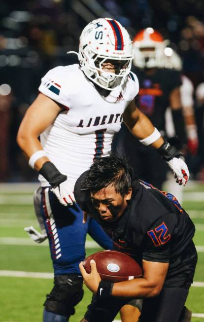 Bishop Gorman quarterback Micah Alejado (12) still tries to run the ball after getting his helm ...