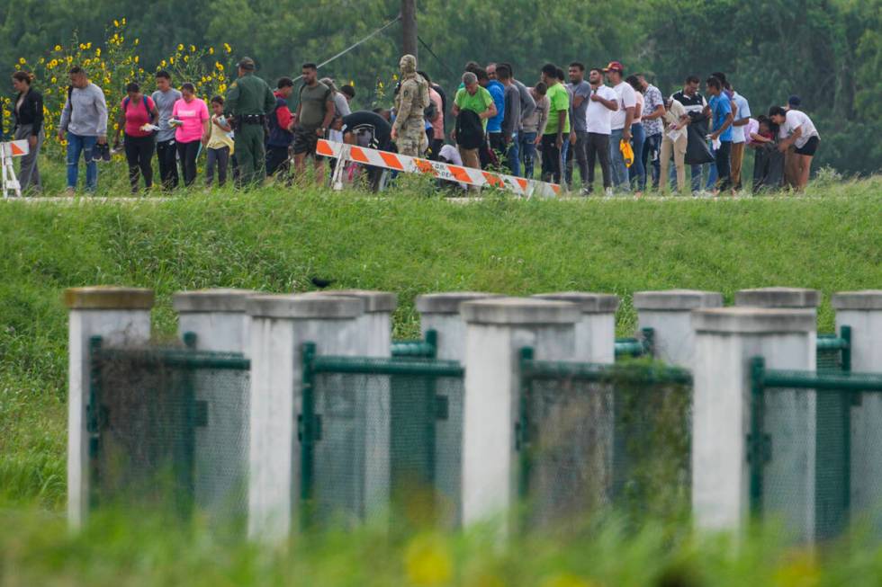 FILE - Migrants talk to officials along a road near the Rio Grande after crossing the Texas-Mex ...