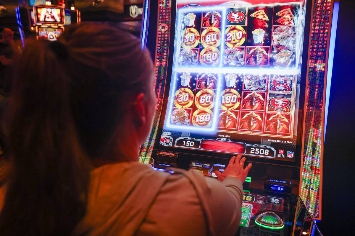 Candice Low, of Washington, plays the first Vegas NFL slot machine at the M Resort in Las Vegas ...
